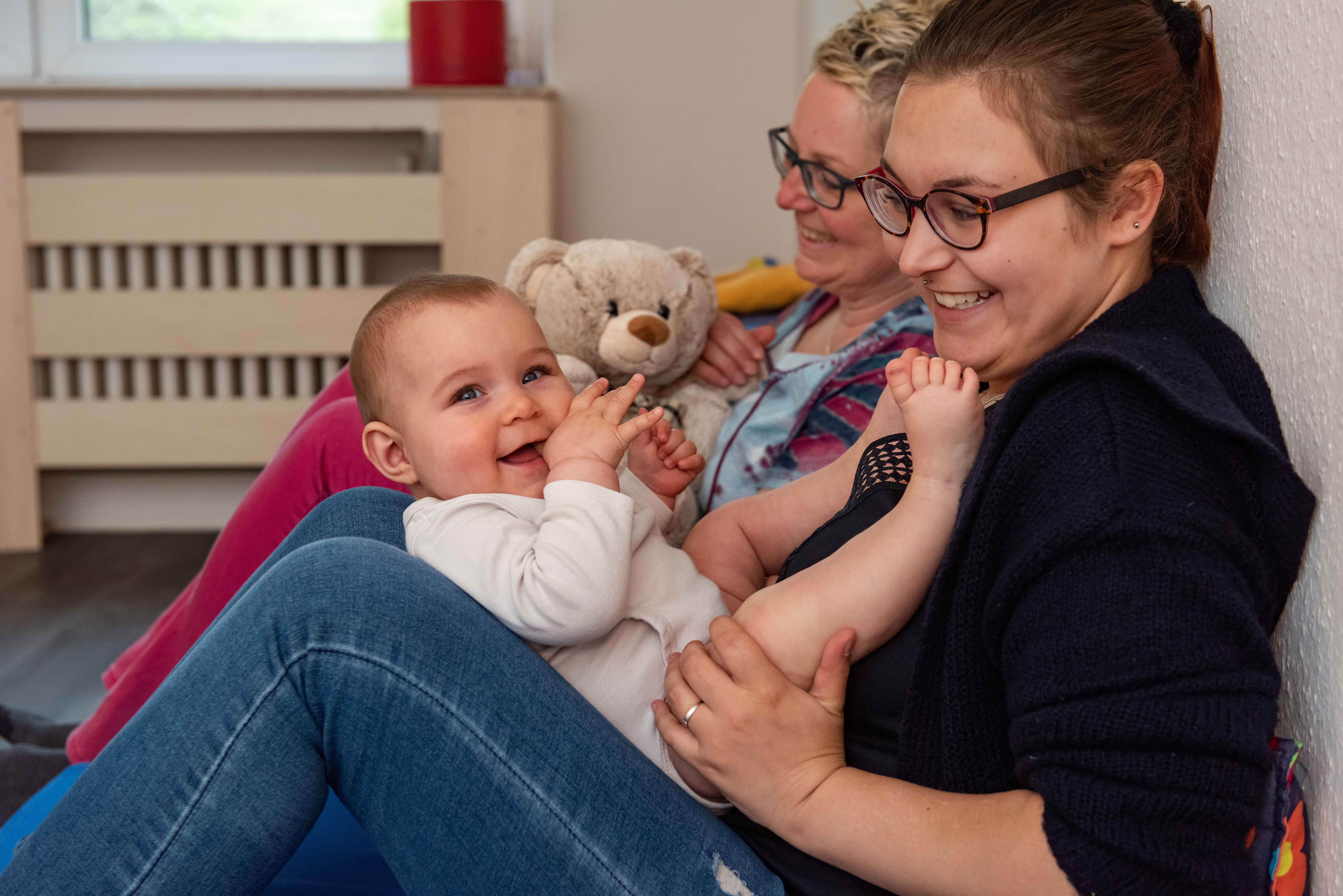 Eine Frau hält ein glücklich lächelndes Baby auf dem Schoß.