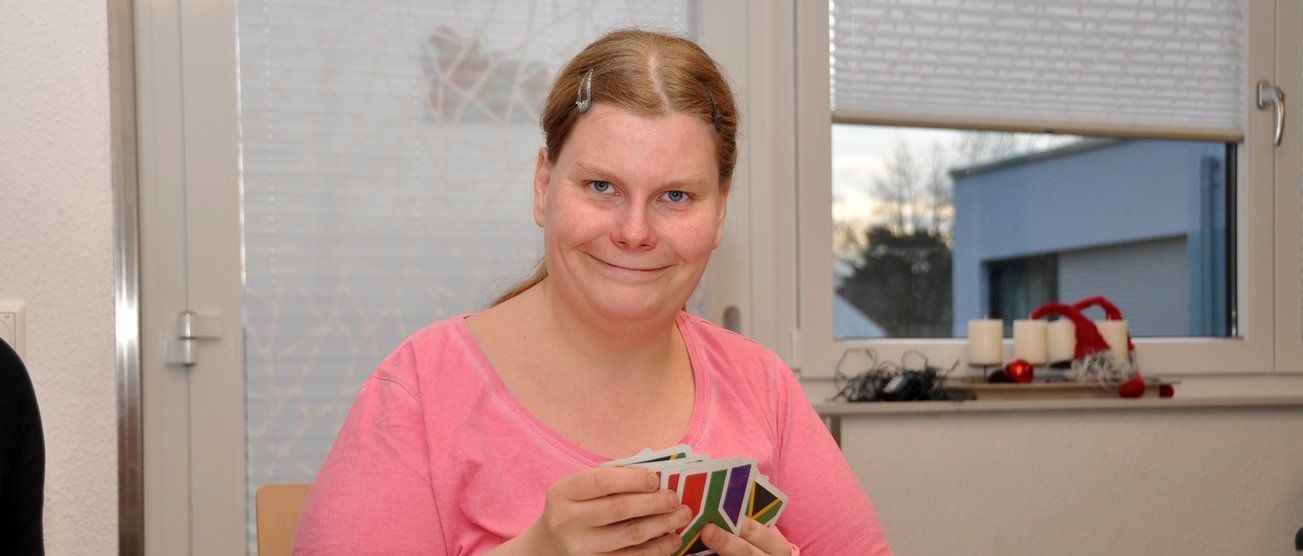Eine lächelnde Frau sitzt an einem Tisch und sortiert ein Kartenspiel. DSC_0987_HSH.jpg