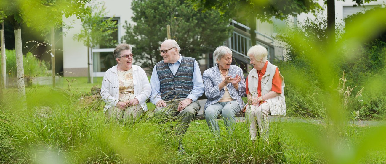 Vier Bewohner eines Altenheims sitzen an einem See auf einer Bank und unterhalten sich. Bottrop-211.jpg
