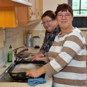 Zwei Frauen stehen lächelnd in einer Küche und machen den Abwasch.