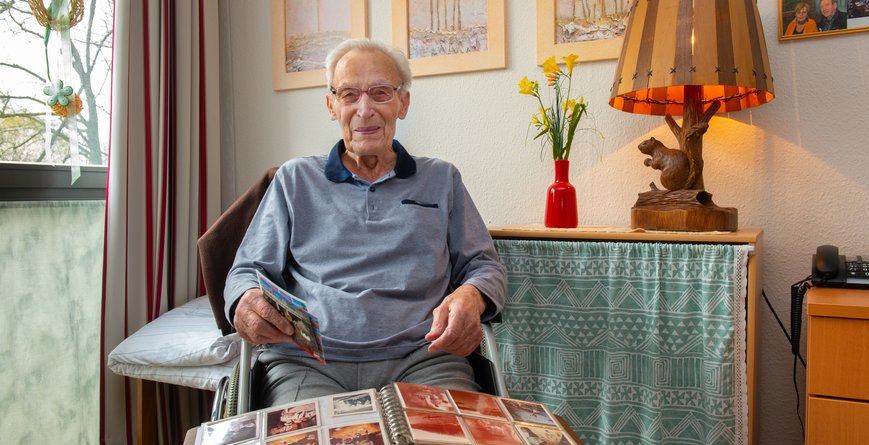 Ein Mann im besten Alter schaut sich lächelnd ein Fotoalbum an.