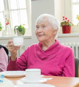 Zwei Frauen im besten Alter sitzen an einem Tisch und trinken Kaffee.