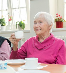 Zwei Frauen im besten Alter sitzen an einem Tisch und trinken Kaffee.