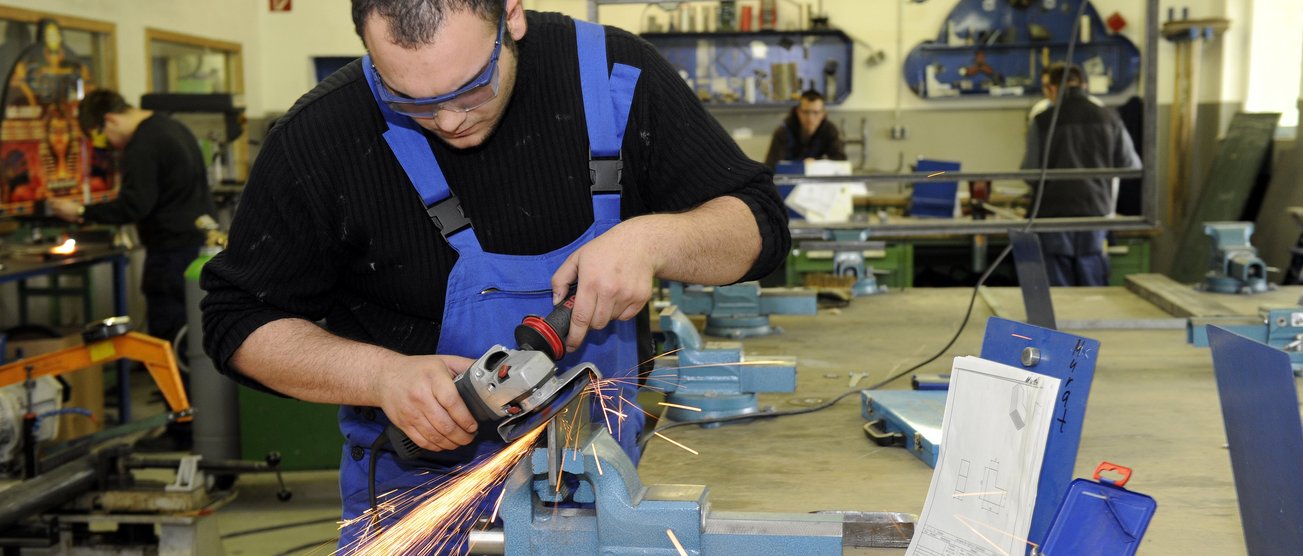 Ein Mann arbeitet konzentriert in einer Metallwerkstatt mit einem Winkelschleifer. 100505_DKW_BOT_460.JPG