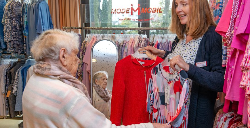 Eine Frau im besten Alter lässt sich in einer Modeboutique von einer freundlichen Verkäuferin beraten.