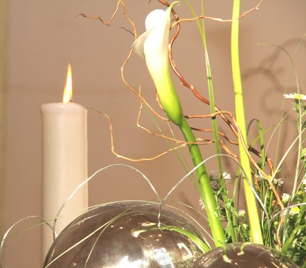 Ein Kirchenaltar mit Blumenstrauß und  brennender Kerze.